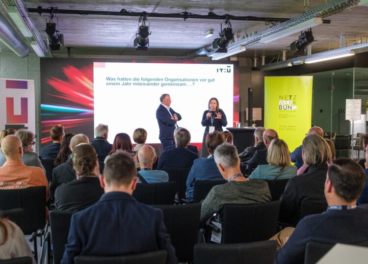 Vortrag vor Publikum bei einer Netzwerkveranstaltung mit Präsentation im Hintergrund