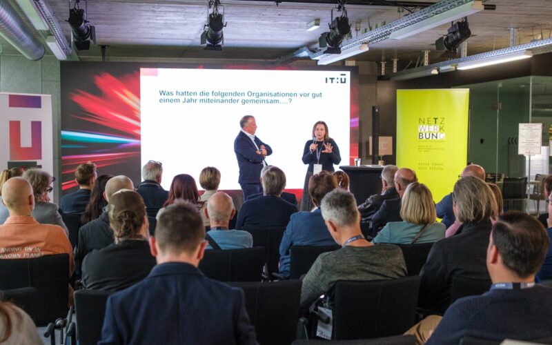 Vortrag vor Publikum bei einer Netzwerkveranstaltung mit Präsentation im Hintergrund