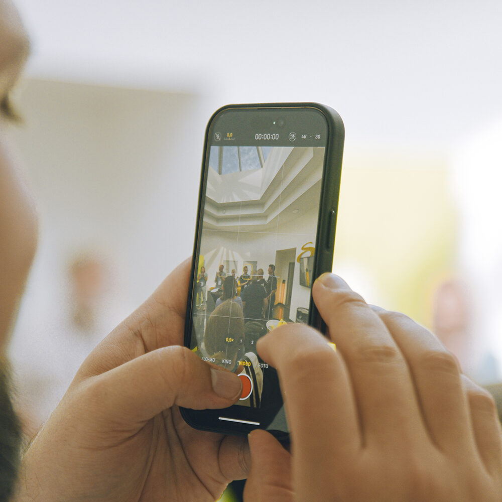Person filmt Präsentation mit Smartphone
