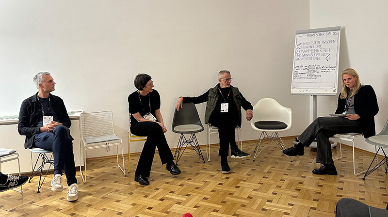 Vier Personen befinden sich in Agenturräumlichkeiten