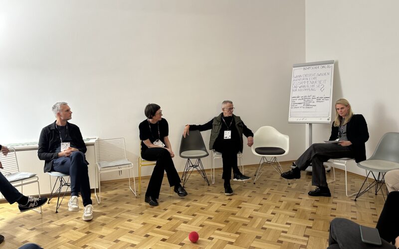 Vier Personen befinden sich in Agenturräumlichkeiten