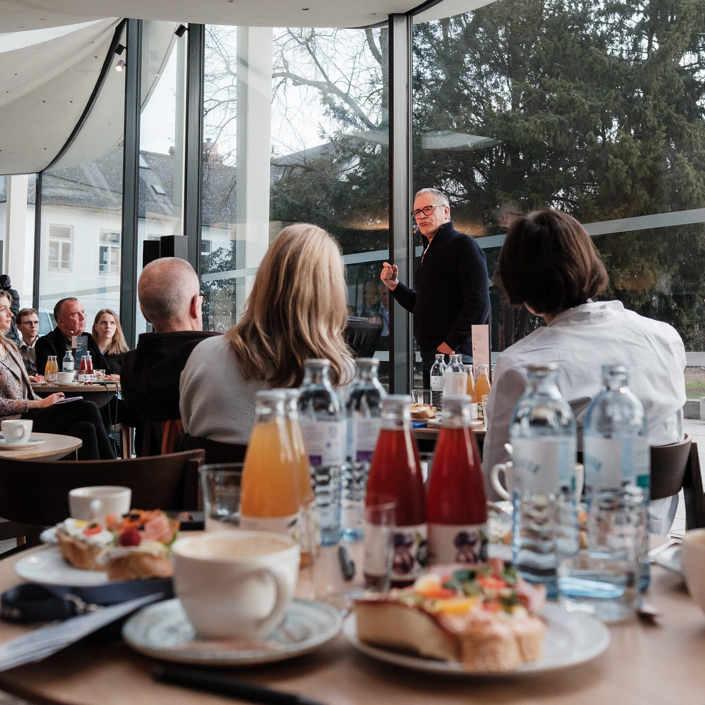 Der Vortragende aus der Perspektive eines Zuhörers beim Frühstückstisch