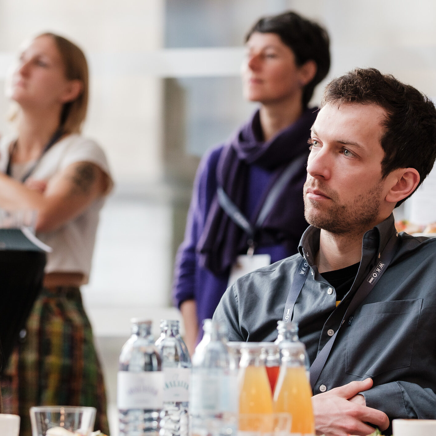 Ein interessierter Zuhörer im Vordergrund, hinten weitere Menschen unscharf