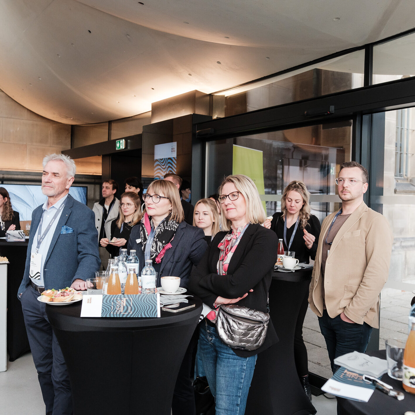 Eine Gruppe von Menschen leger bei Stehtischen