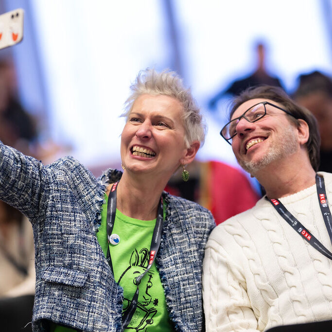 Zwei Personen des Publikums machen zusammen ein Selfie mit dem Smartphone