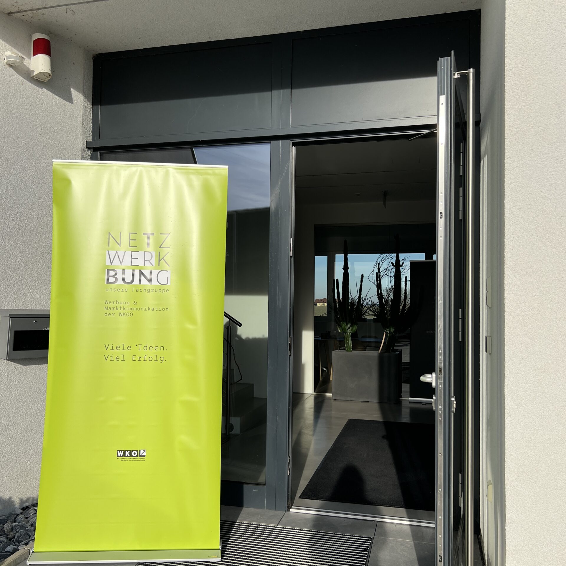 Eingangsbereich des webdot Büros mit einem hellgrünen Netzwerk Werbung Banner