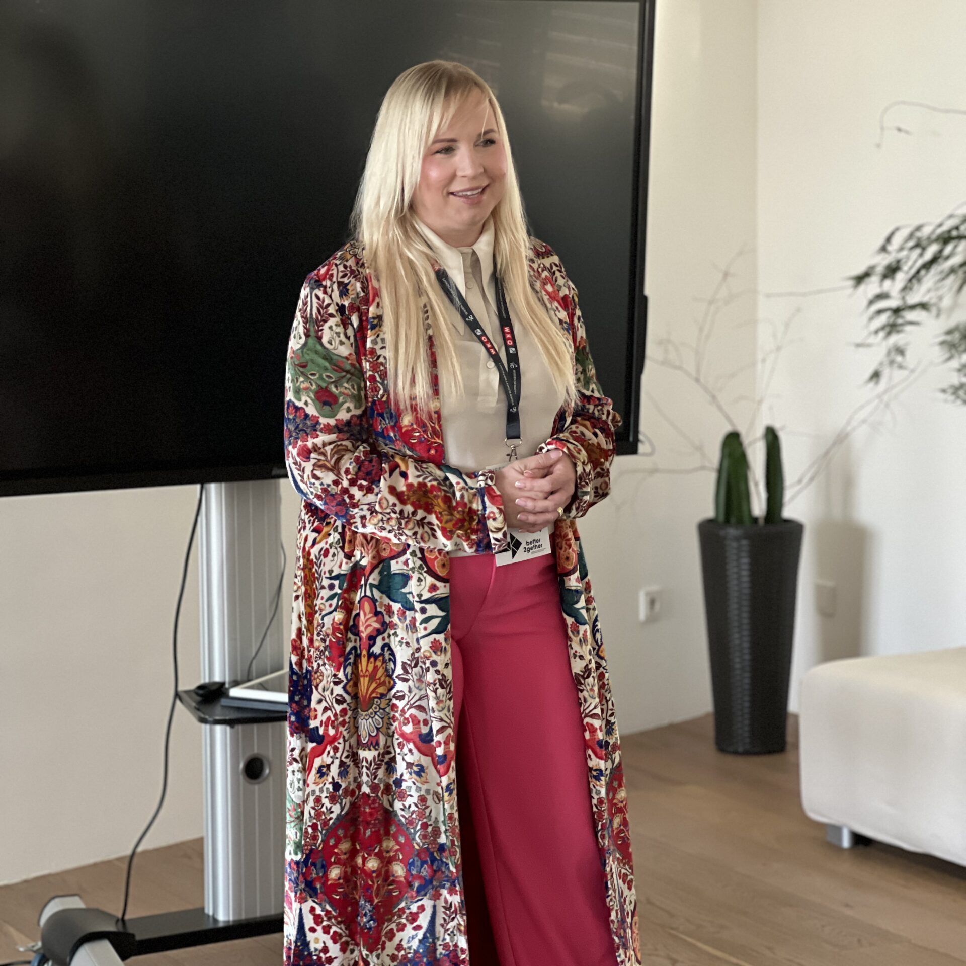 Eva Wöckl steht in einem Großraumbüro vor einem Präsentations-Screen
