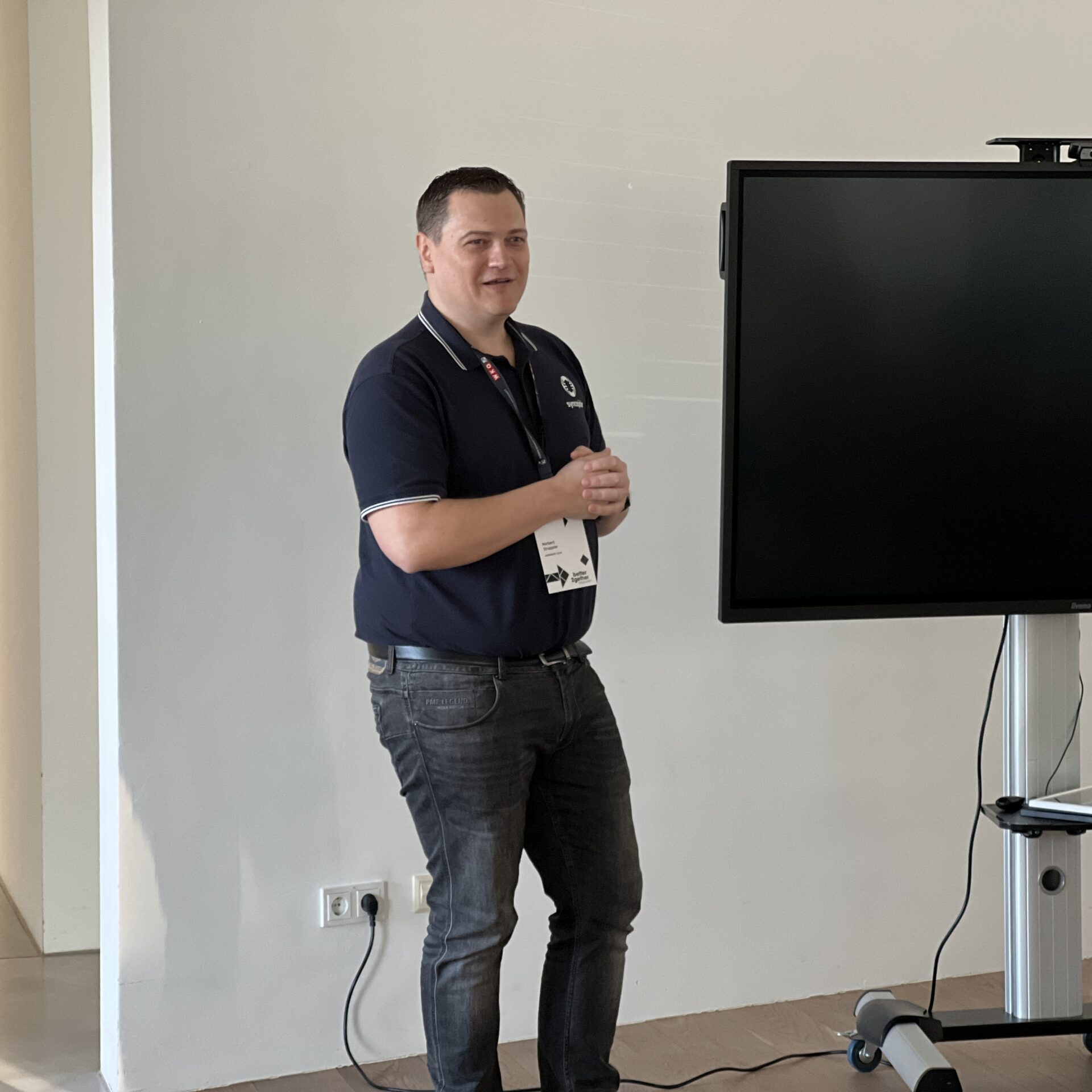 Norbert Strappler steht in Büroräumlichkeiten neben einem Bildschirm-Screen