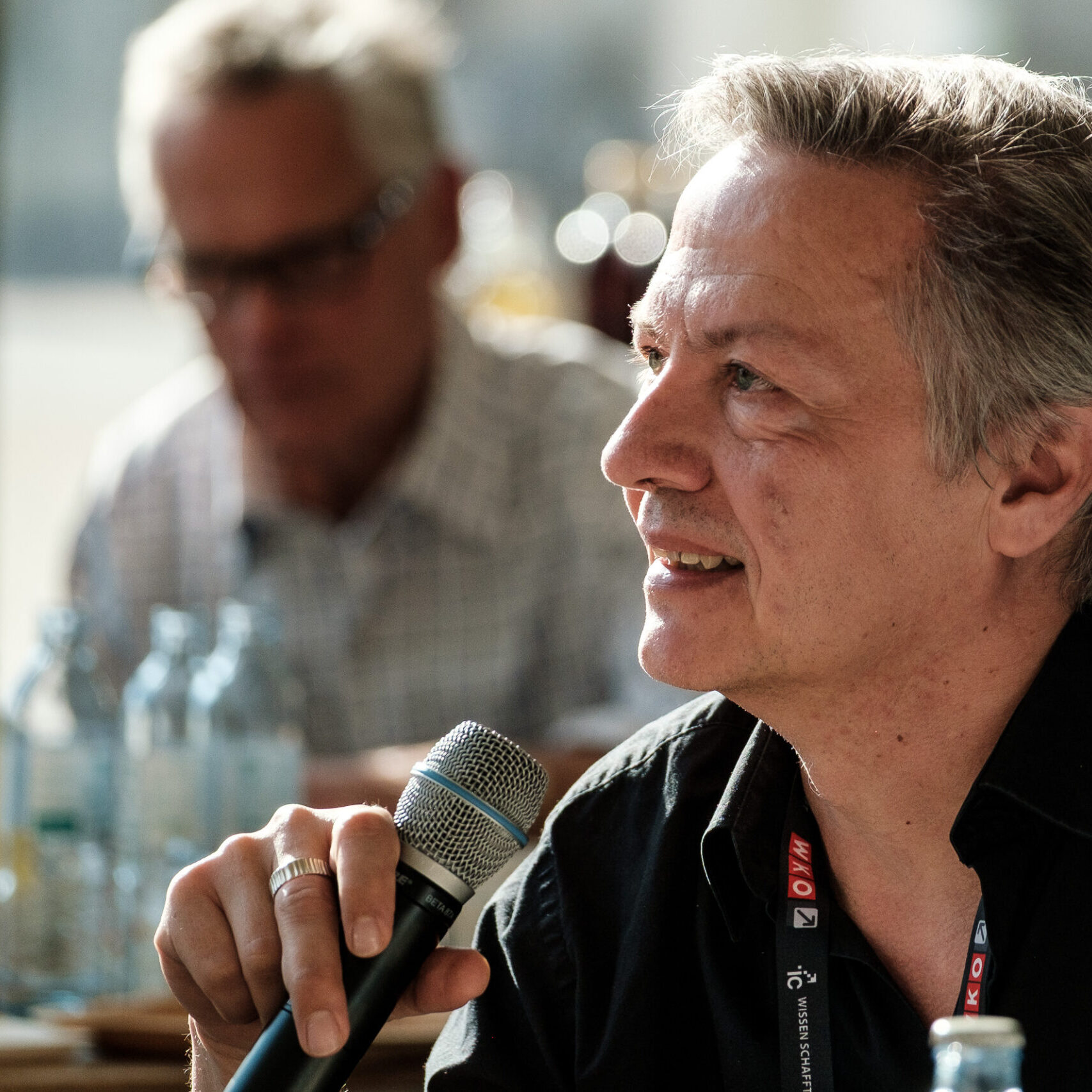 Denkfrühstück-Teilnehmer spricht in Mikrofon; im Hintergrund ist ein weiterer Teilnehmer zu sehen