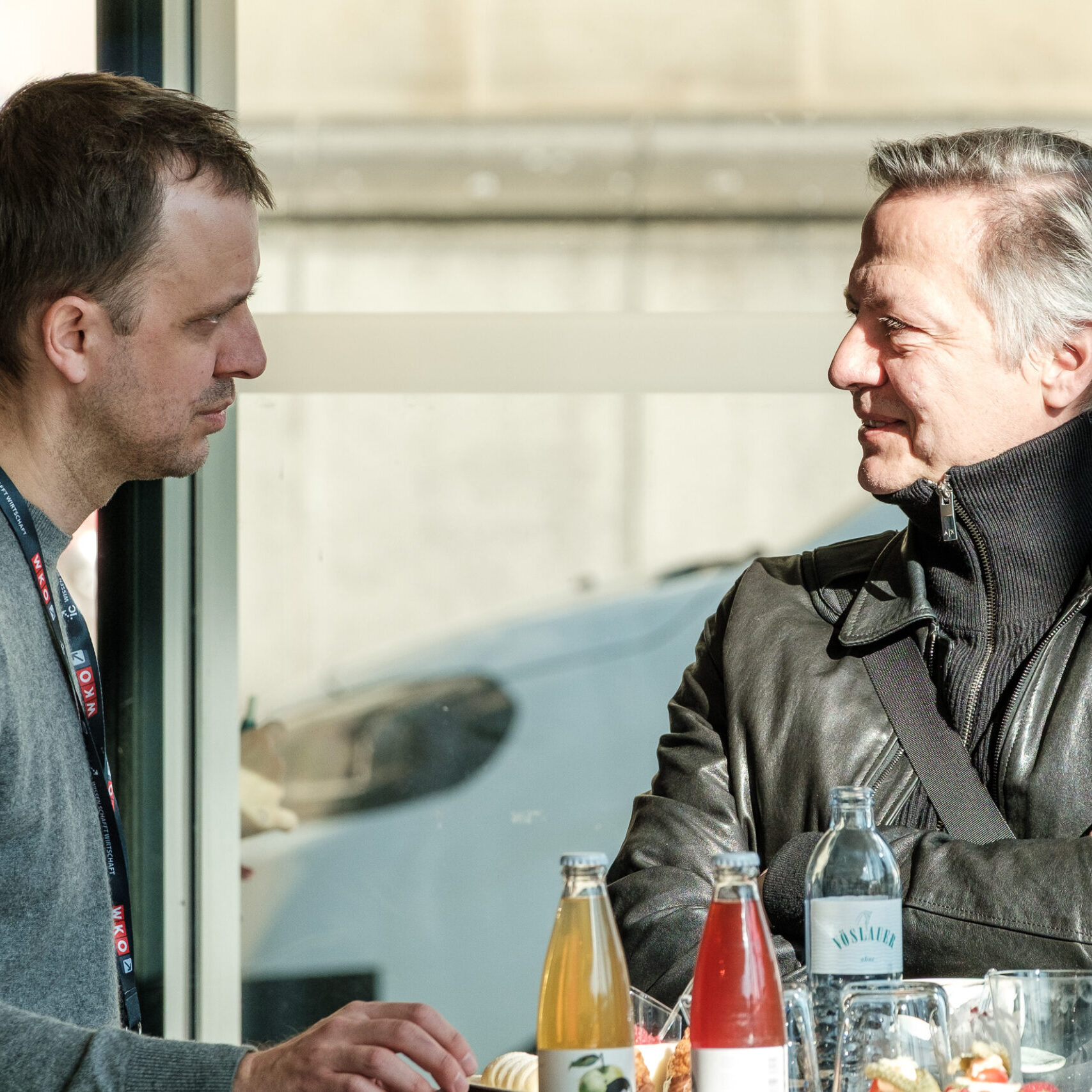 Zwei Denkfrühstück-Besucher sprechen miteinander; davor sind Getränke auf einem Tisch zu sehen
