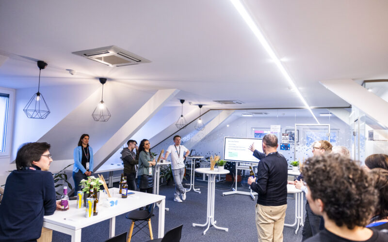 Cyberhouse-Büroräumlichkeiten mit einem Bildschirm, Stehtischen und Gästen