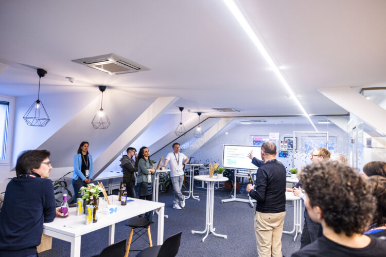 Cyberhouse-Büroräumlichkeiten mit einem Bildschirm, Stehtischen und Gästen