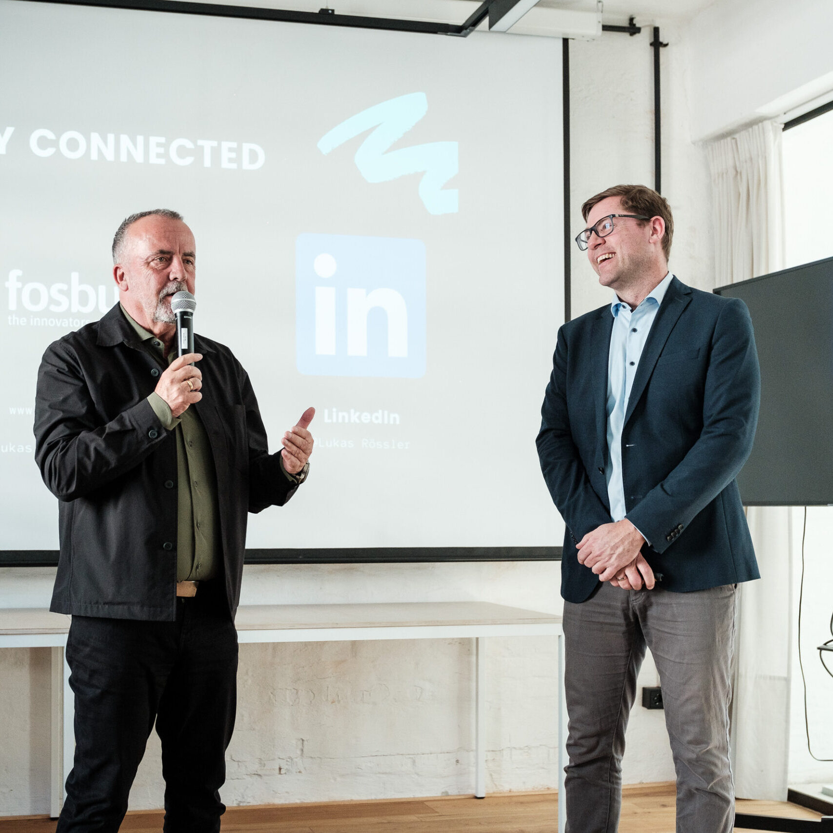 Christoph Schumacher steht mit Speaker Lukas Rössler vor Präsentationsscreen