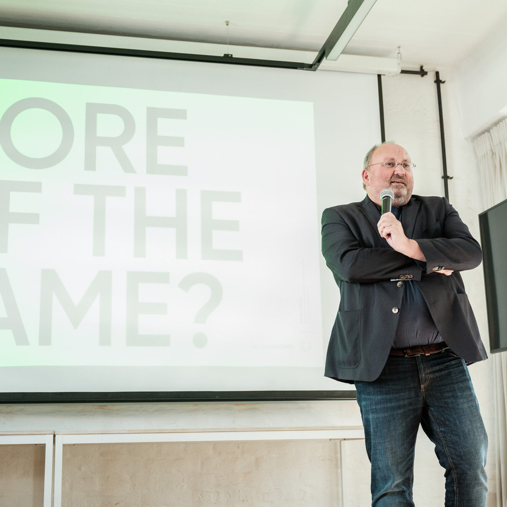 Thomas Börgel steht mit einem Mikrofon vor einer Präsentation