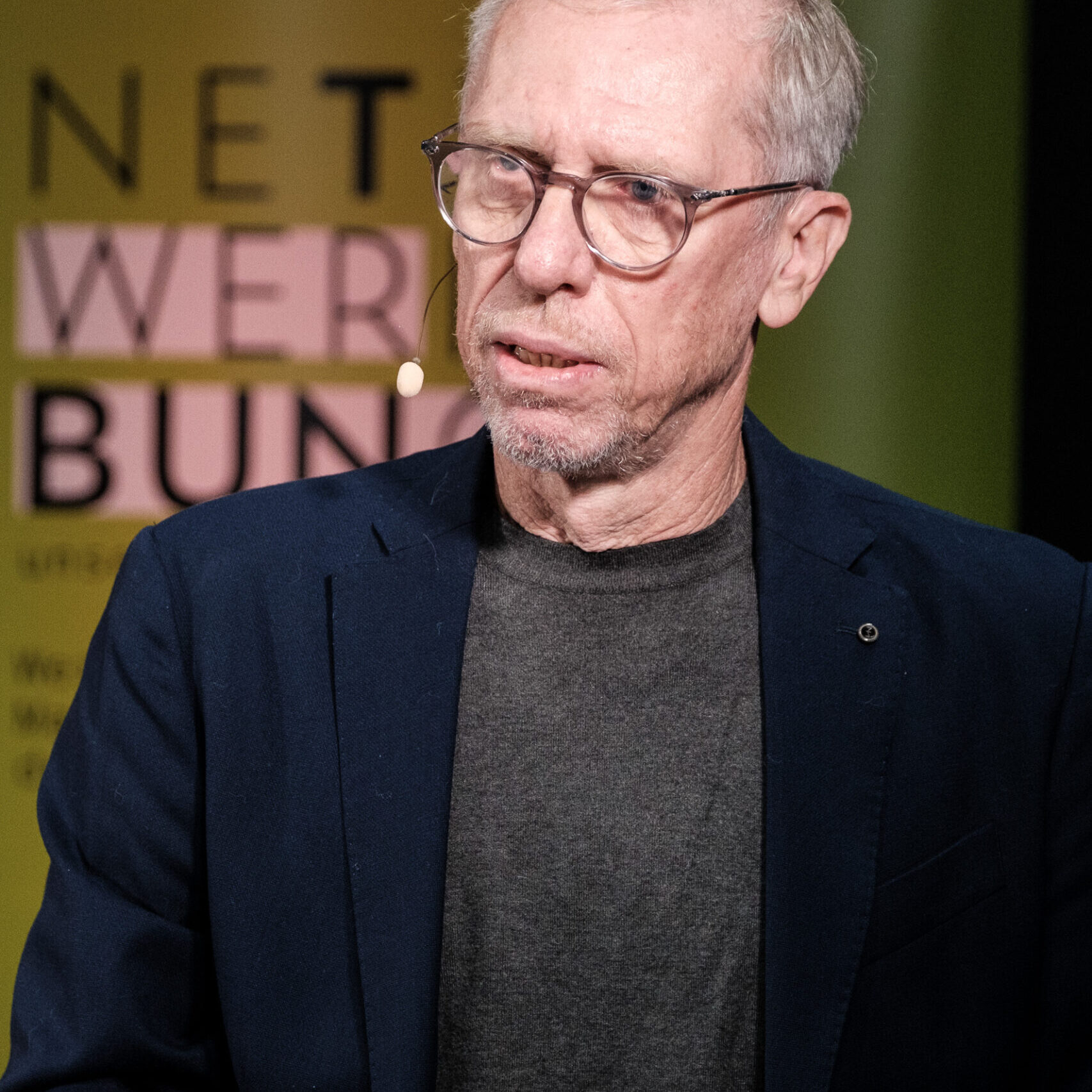 Peter Stöger im Porträt vor einem Netzwerk Werbung Banner