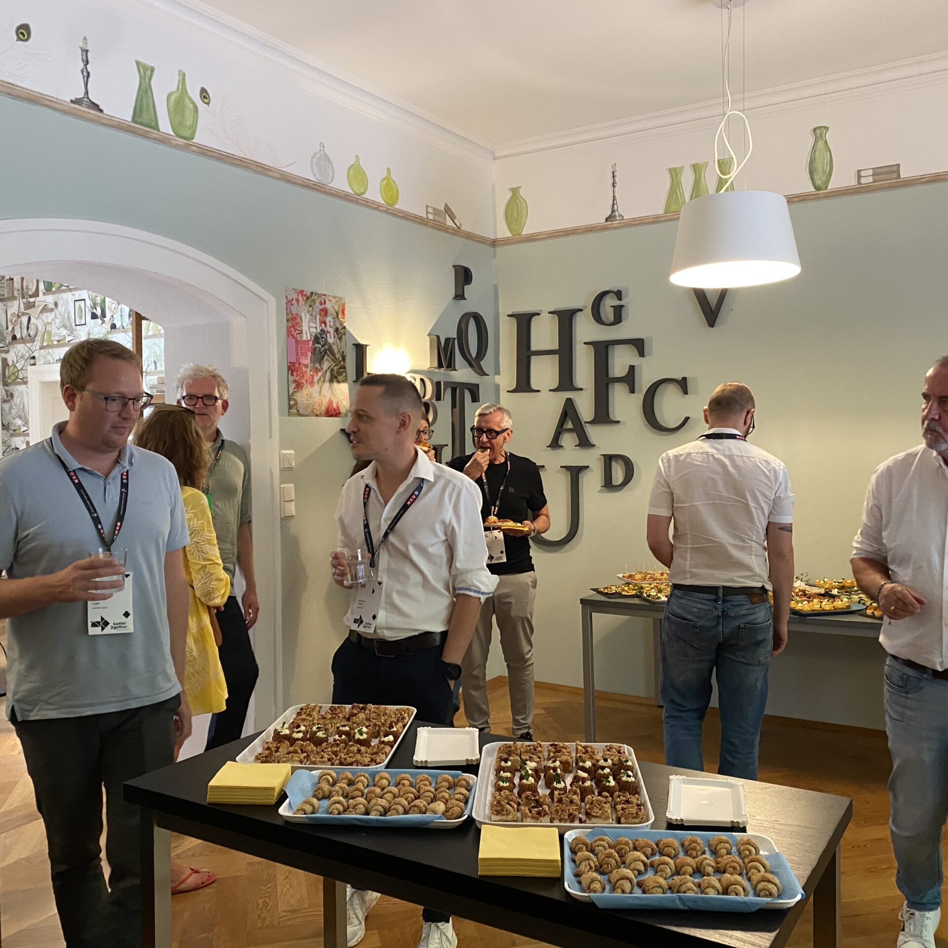 Teilnehmende stehen bei einer Workshop-Pause an einem Buffet und unterhalten sich